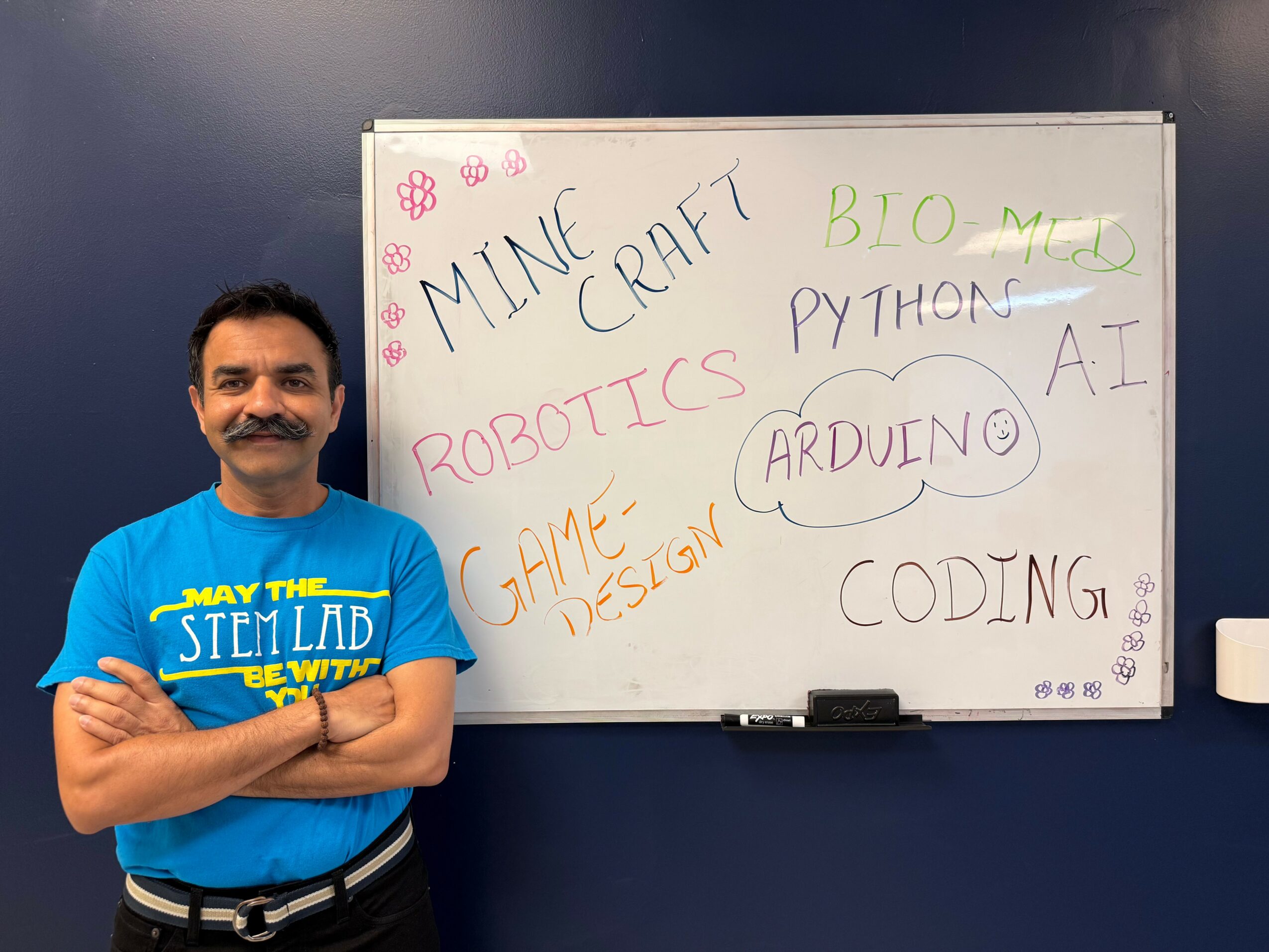 Man standing next to a whiteboard with handwritten words related to technology and programming.