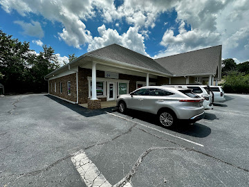 Parking lot with cars in front of a building under a partly cloudy sky.