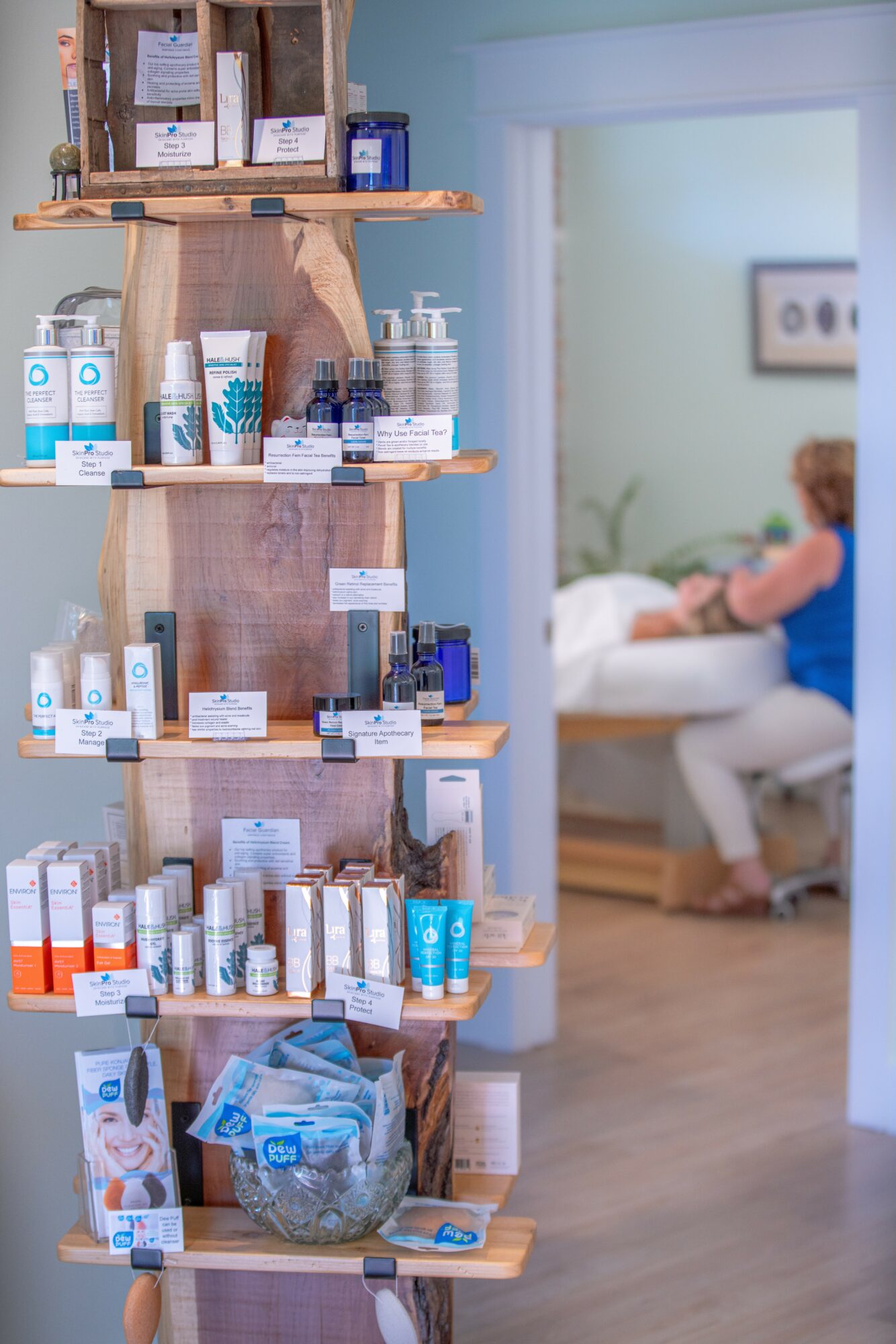 Shelves with skincare products in a store, with a blurred person in a medical or spa setting in the background.