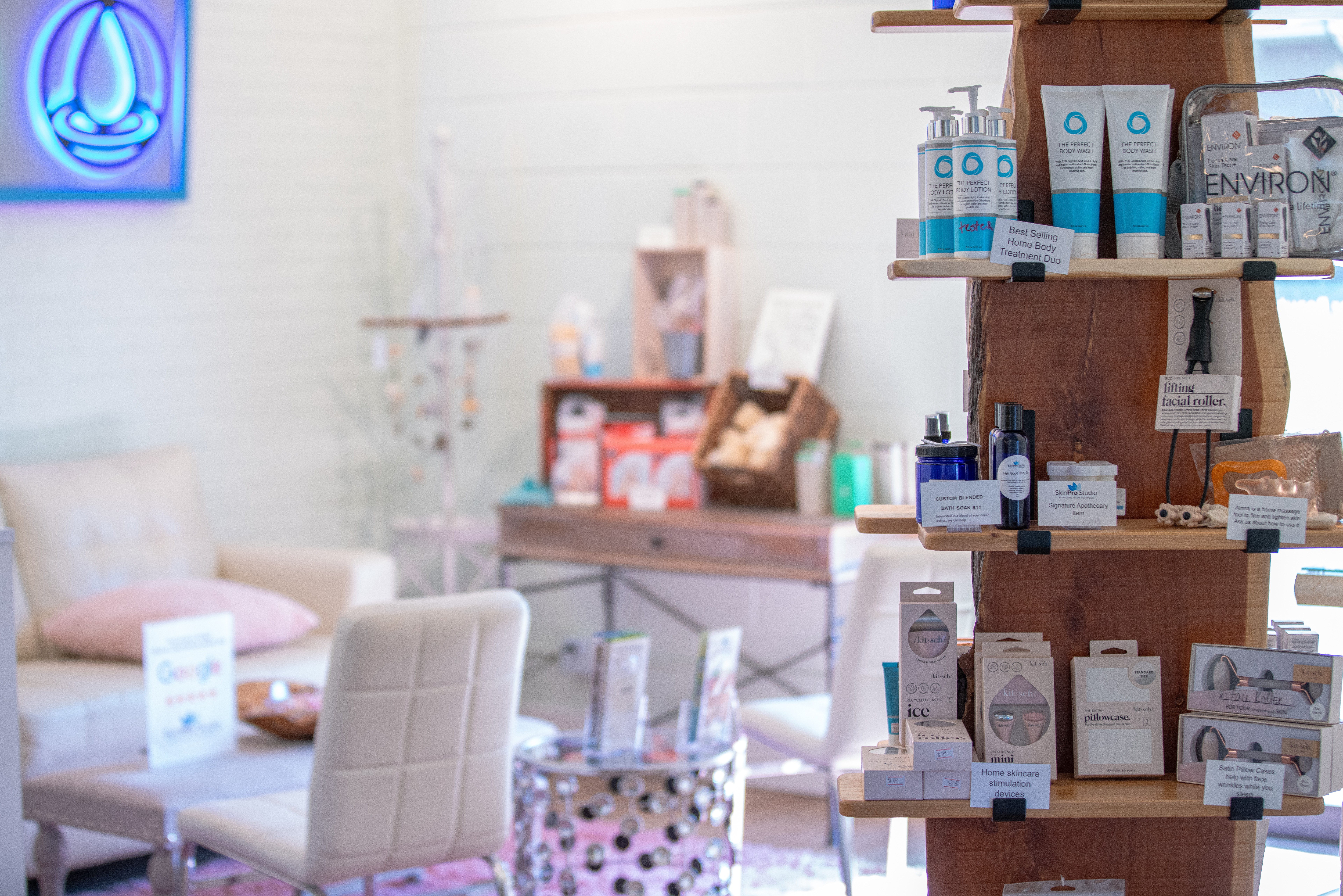 Display of skincare products on wooden shelves in a bright, clean store with seating area in background.