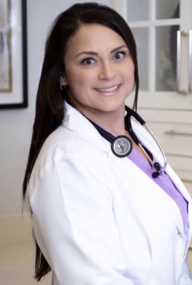 Female healthcare professional with stethoscope smiling in a clinical setting.