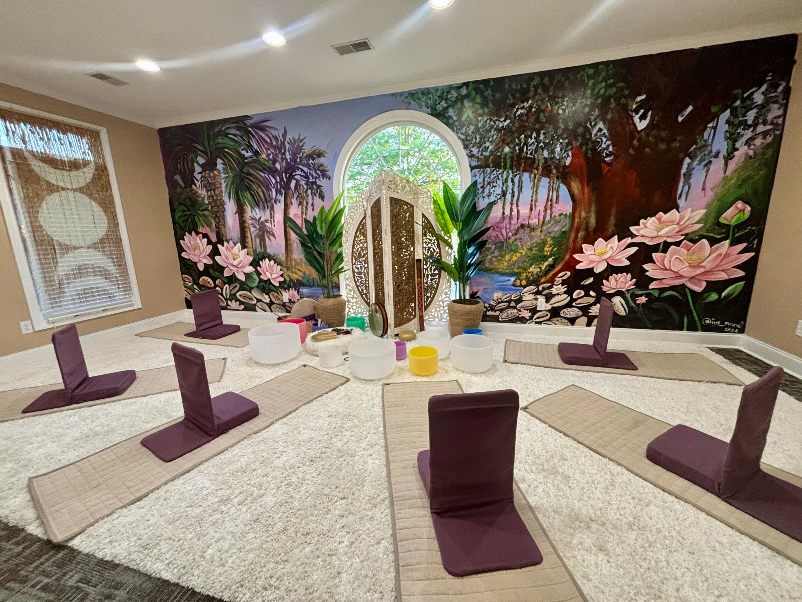 Yoga mats and blocks arranged in a circle in a room with a nature-themed mural wall.