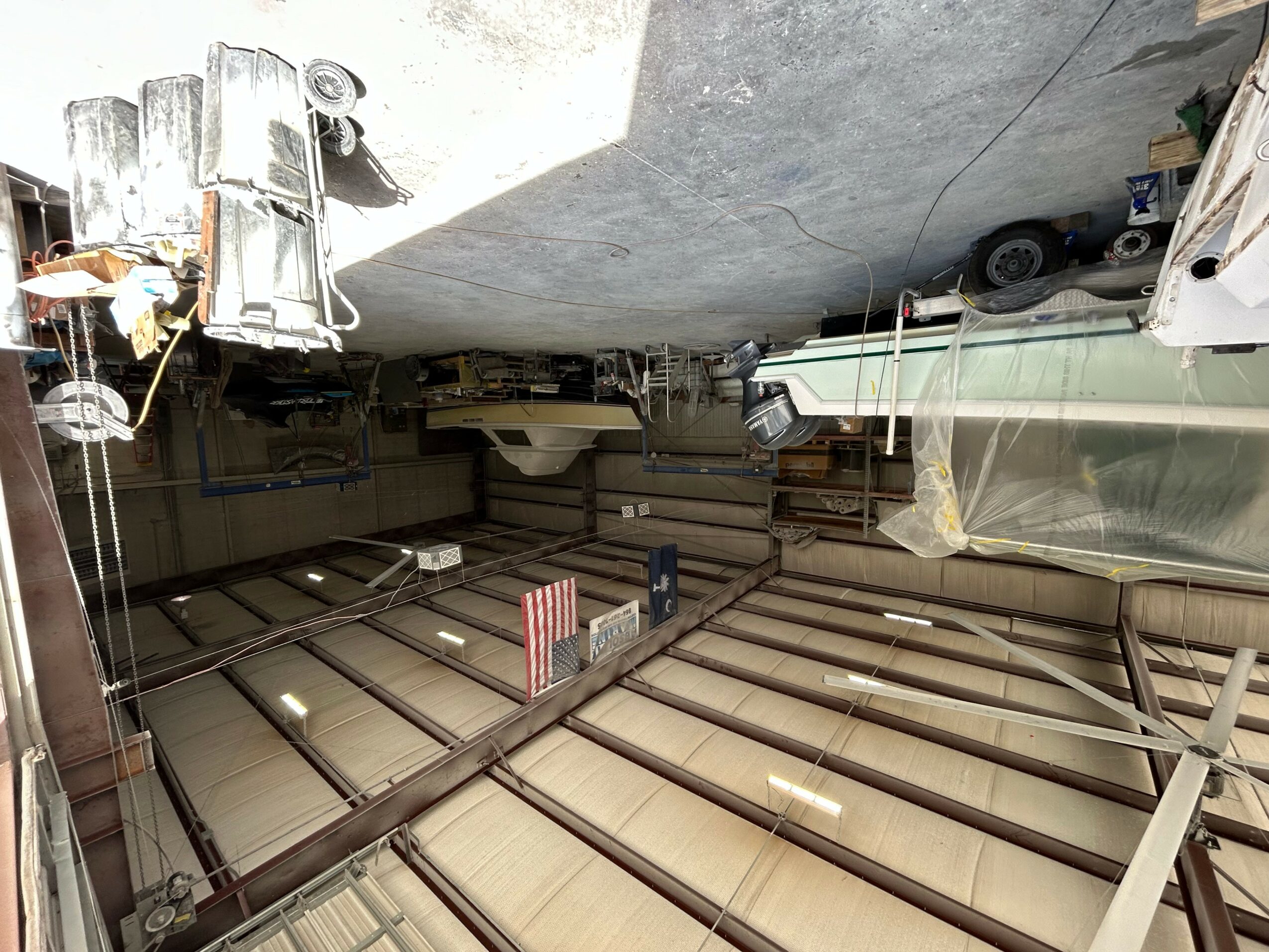 Indoor storage area with boat, equipment, and supplies on a sloped ceiling and floor.