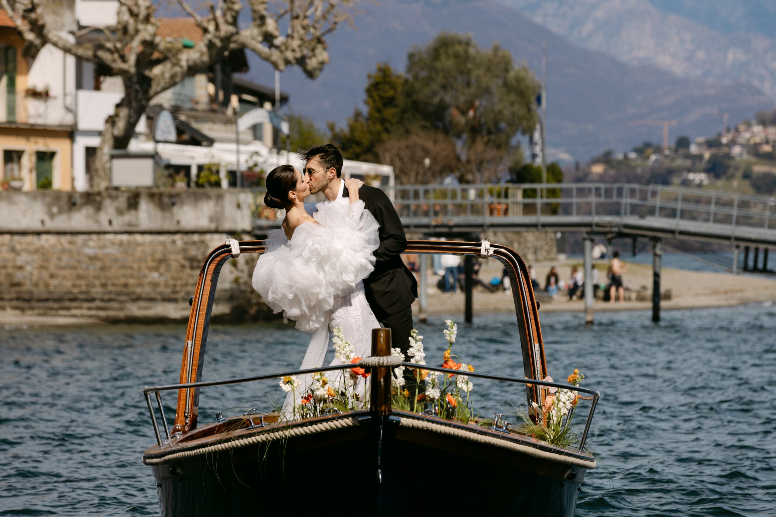 Couple kissing on a boat with water and a bridge in the background.