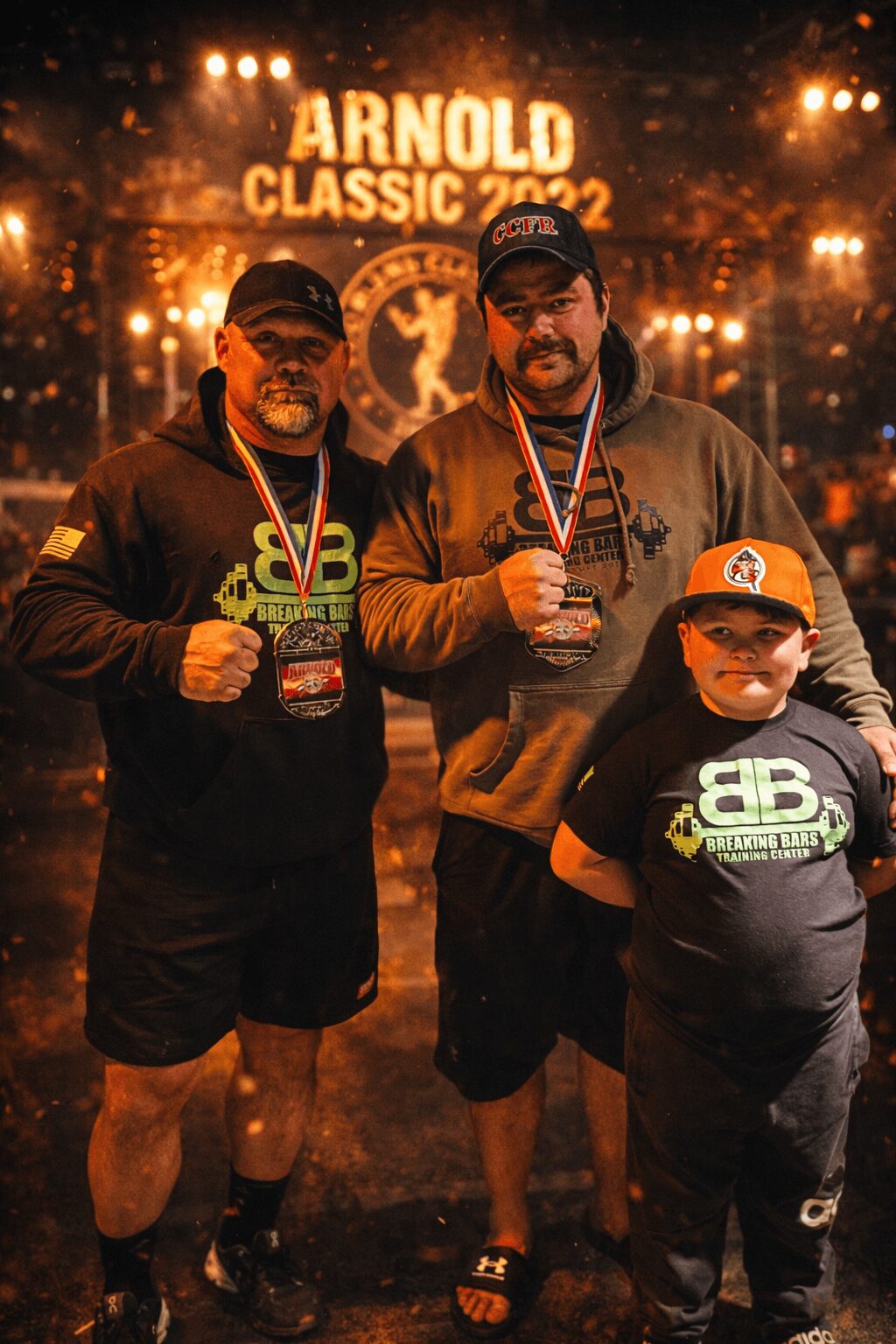 Three people standing with medals in front of a lit sign reading Arnold Classic 2022, at night.
