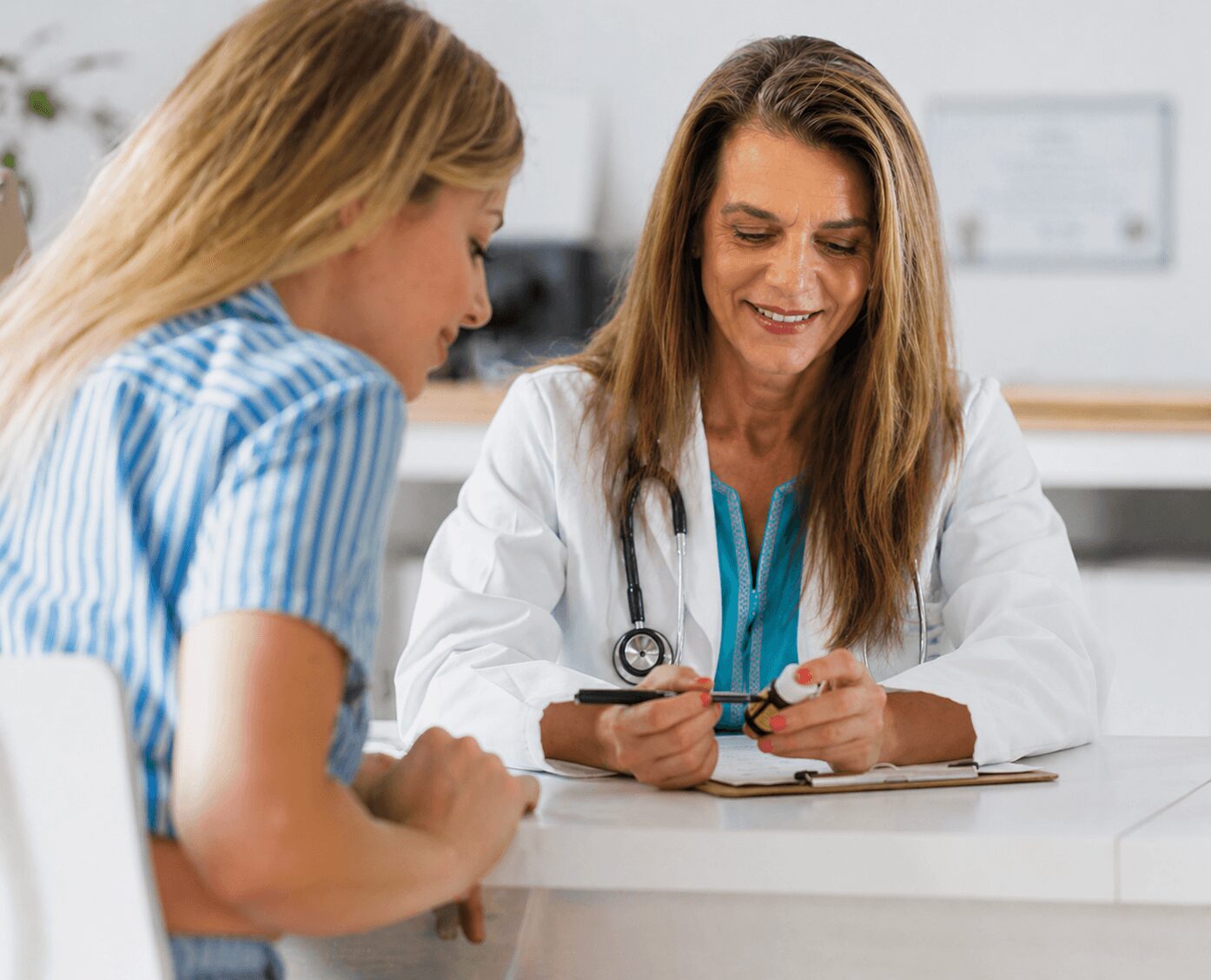 Doctor and patient woman talking at a desk, woman holding a pen, medical office setting.