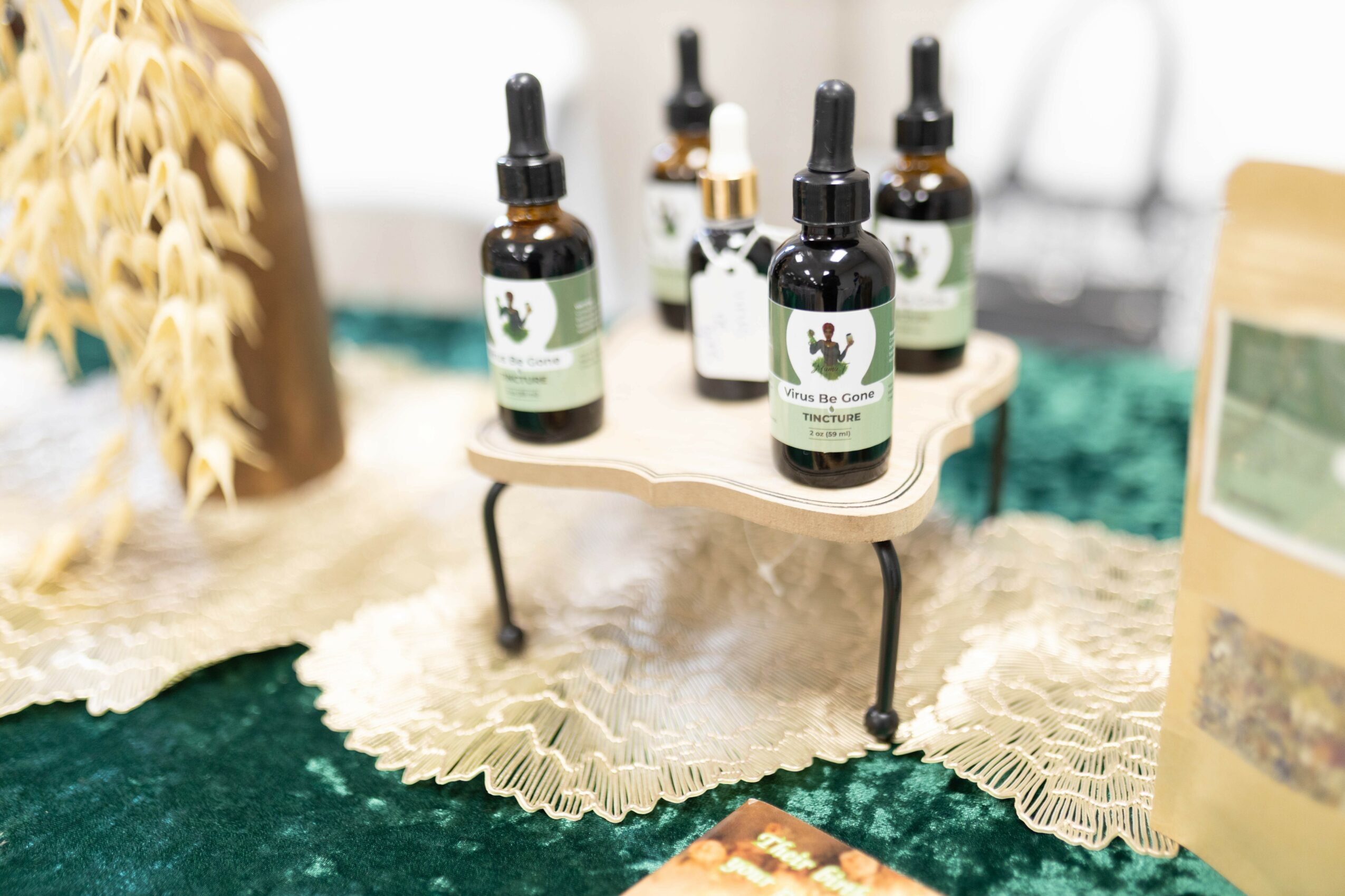 Small bottles of essential oils on a miniature table with a lace cloth, on a green surface.