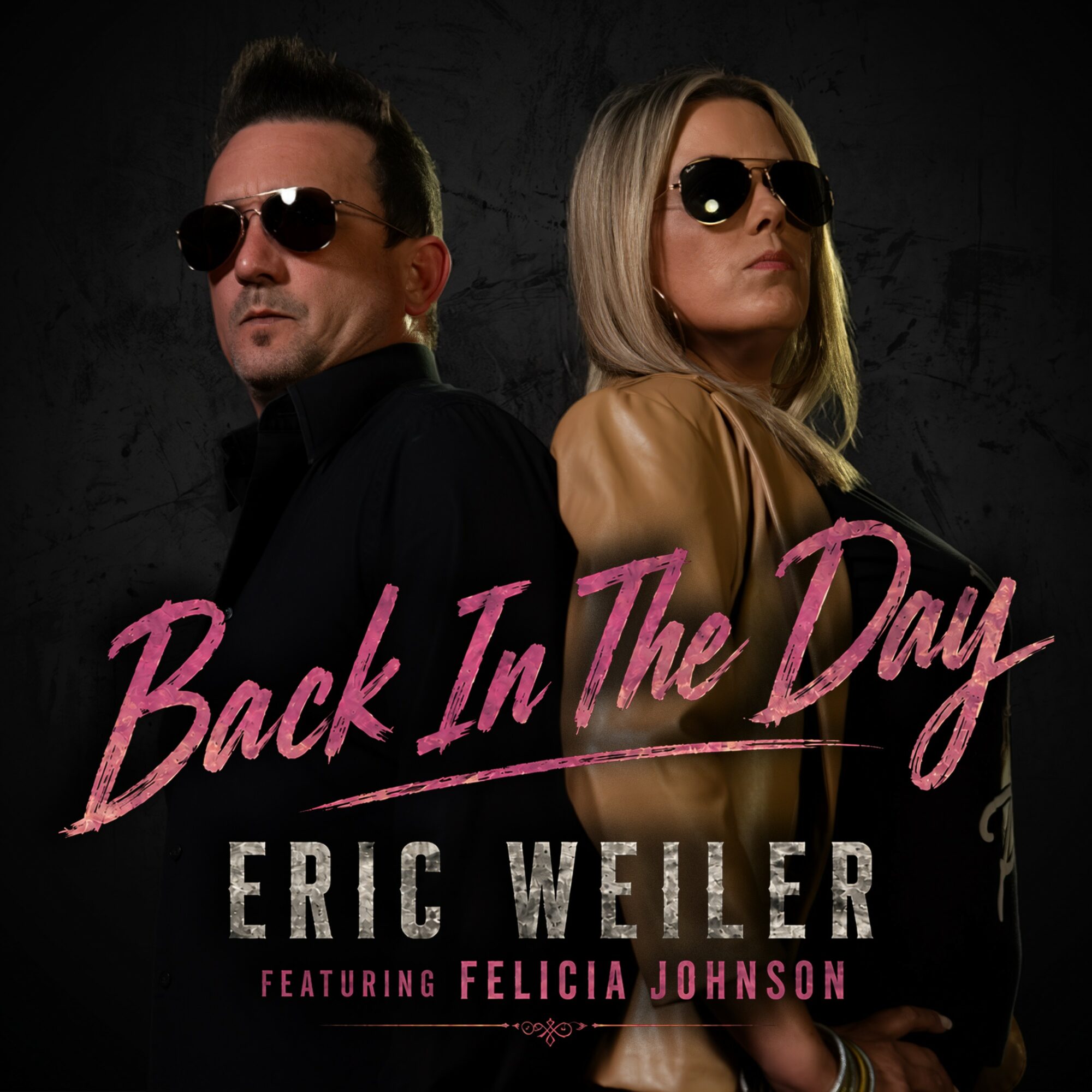 Two people wearing sunglasses, standing back to back against a dark background, with pink and white text overlay.