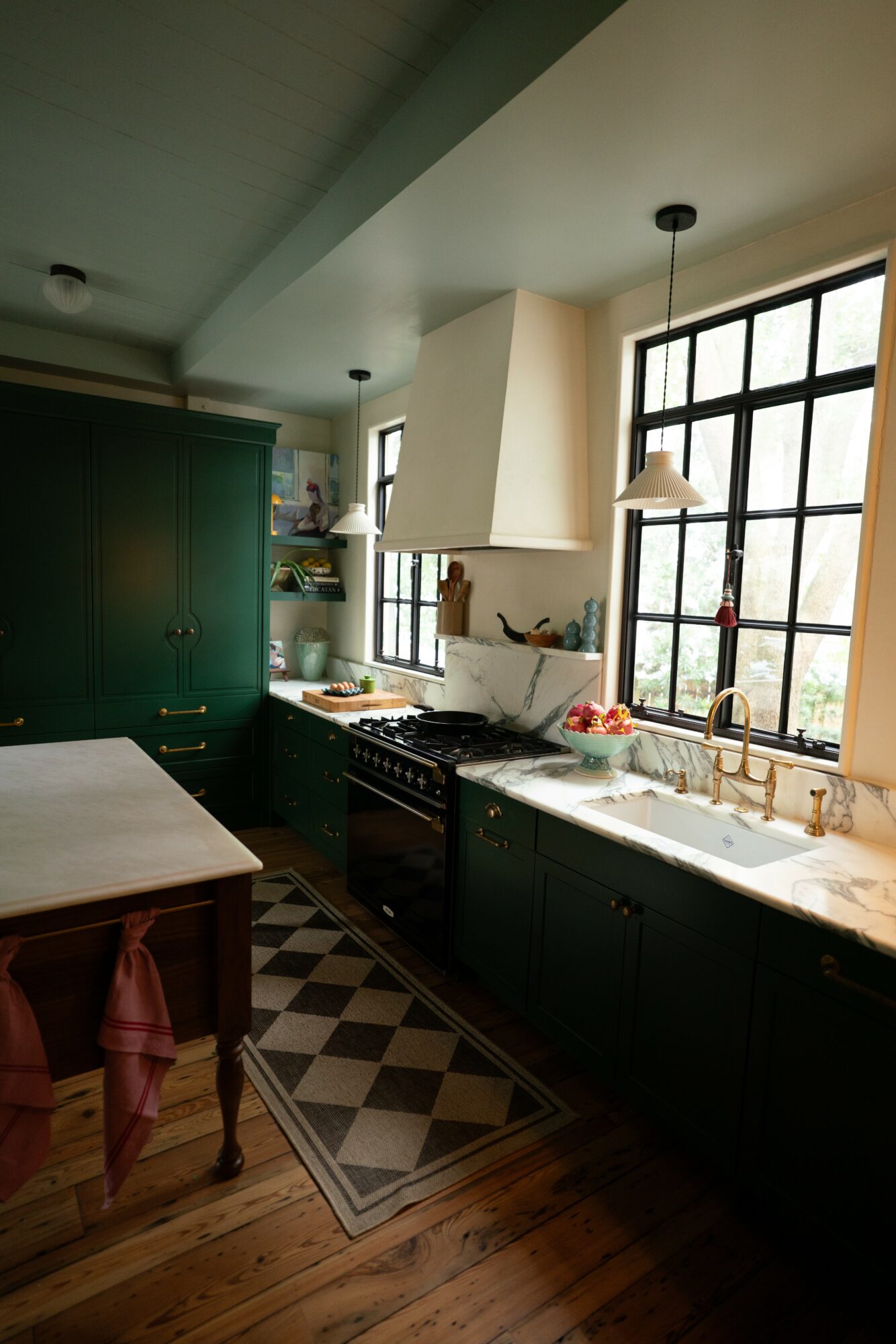 Kitchen with green cabinets, large window, white countertop, and black and white checkered floor.