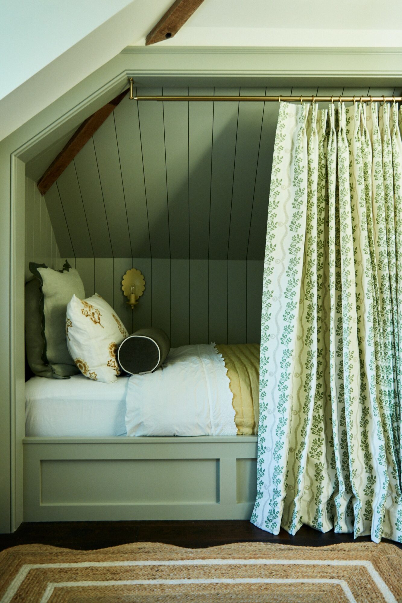 Bedroom corner with bed, pillows, curtains, and sloped ceiling, featuring green and white decor.
