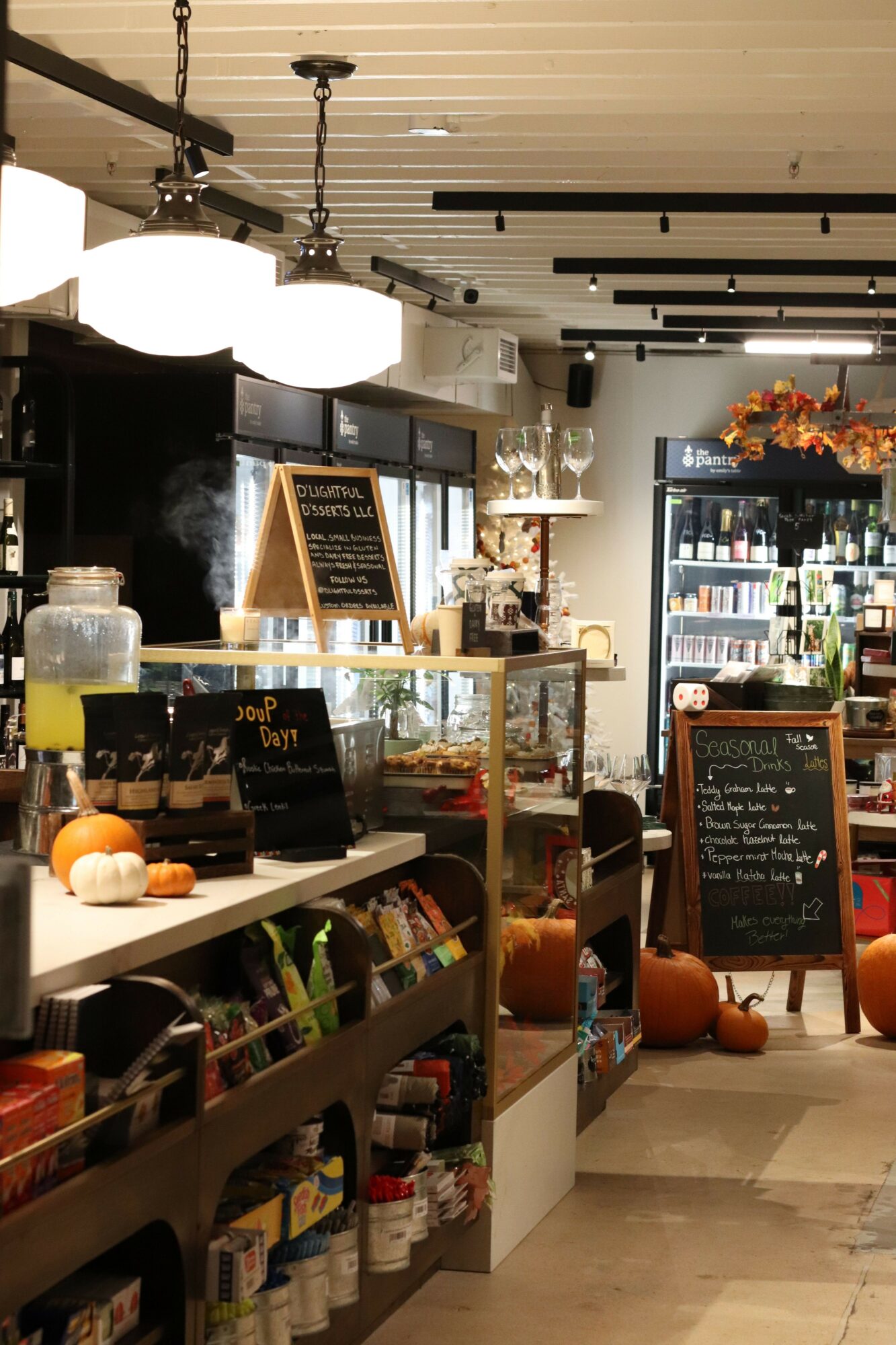 Interior of a store with shelves, a chalkboard sign, and various products displayed, viewed from the side.