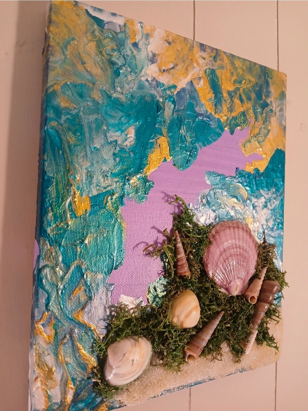 Mixed media artwork with seashells, moss, and cones on a colorful abstract background with pink, blue, yellow, and green hues.