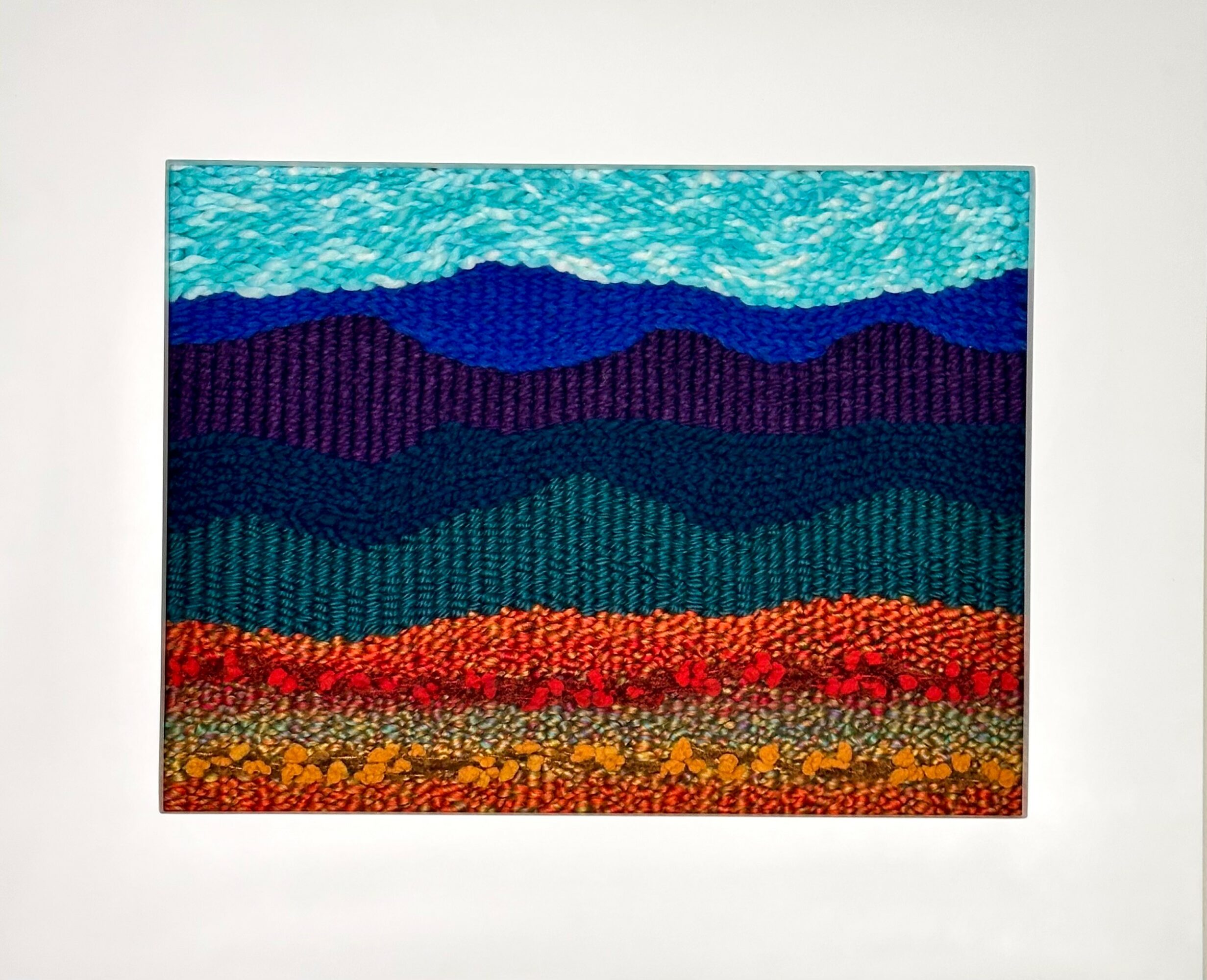 Colorful landscape painting with layered hills in blue, purple, green, red, and yellow, on a white background.