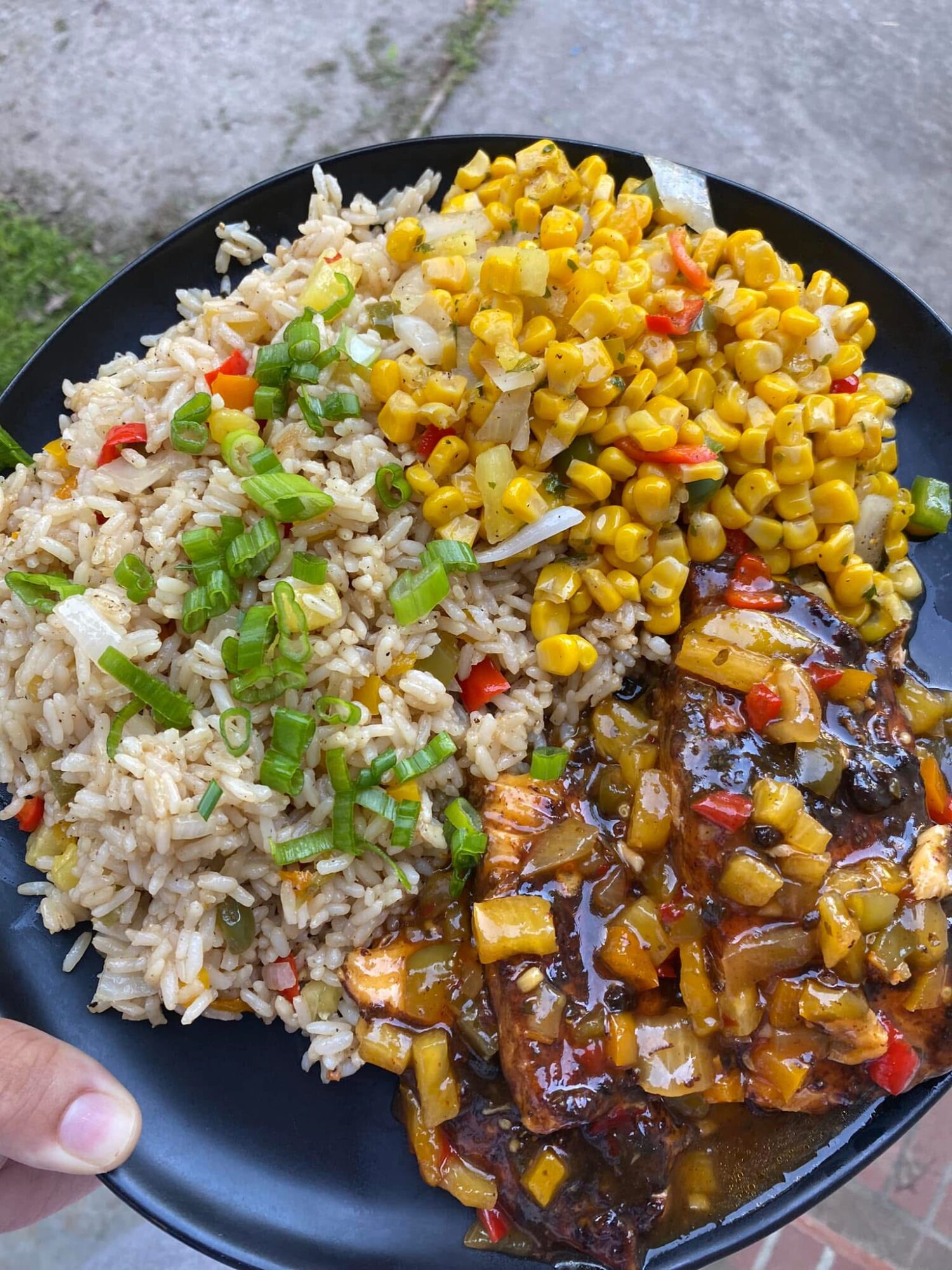 Plate with rice, corn, and a dish with sauce and vegetables, on a gray surface