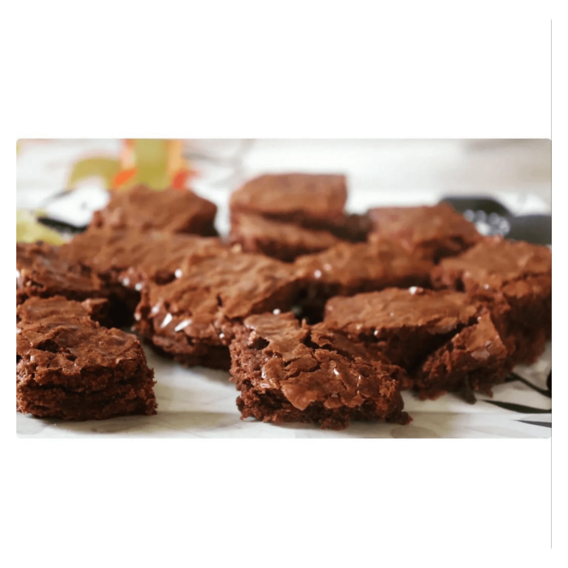 Chocolate brownies broken into pieces on a plate, with a blurred background, close-up view.
