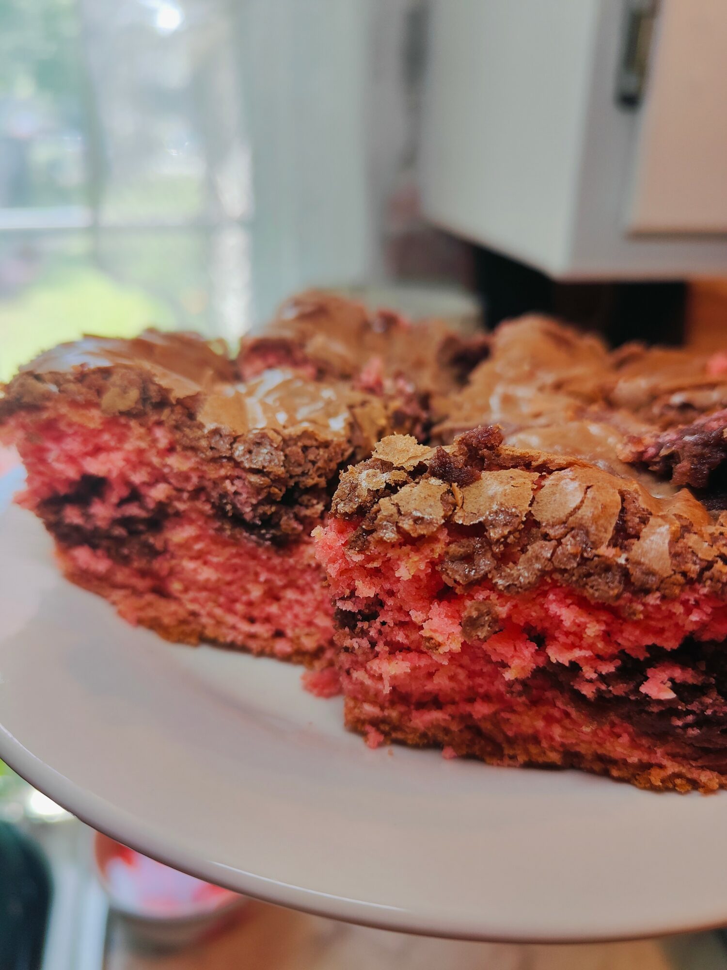 Close-up of a slice of berry crumble dessert with a crumbly topping on a white plate, background blurred.