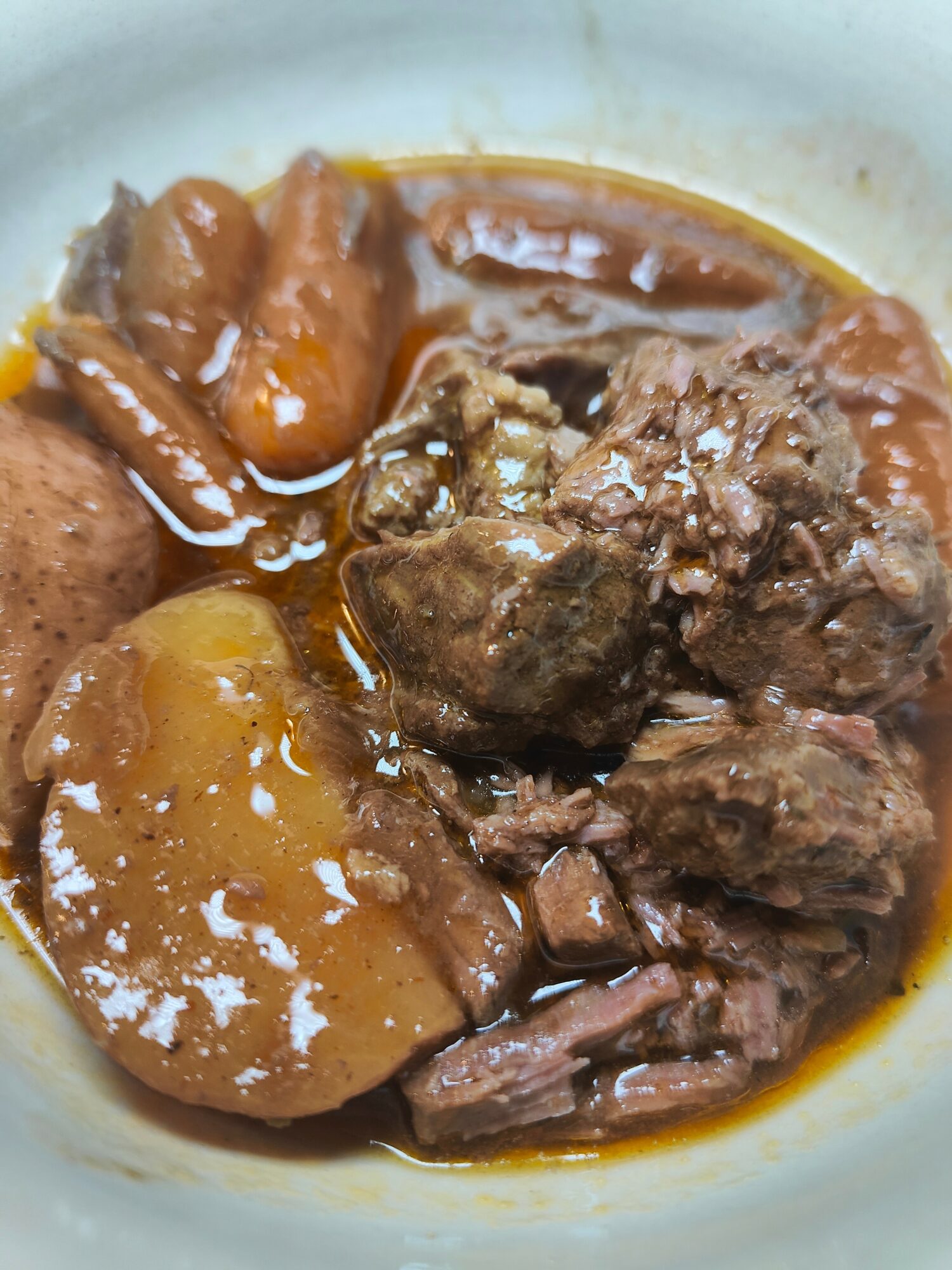 Stew with chunks of meat, potatoes, and vegetables in a brown sauce in a bowl.