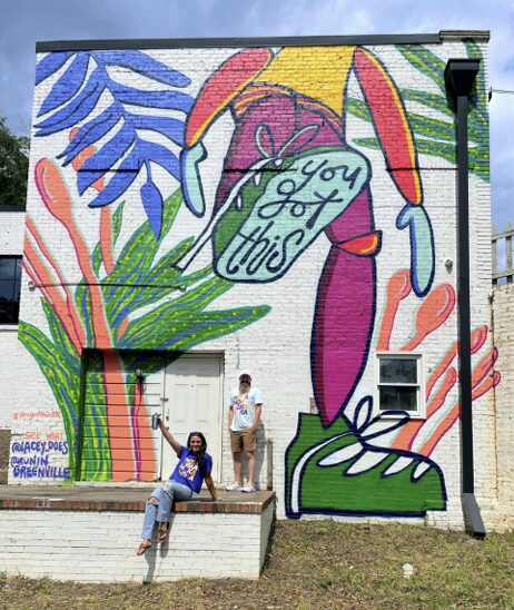 Colorful mural with large flower, leaves, and a person holding a sign that says 'You Got This'.