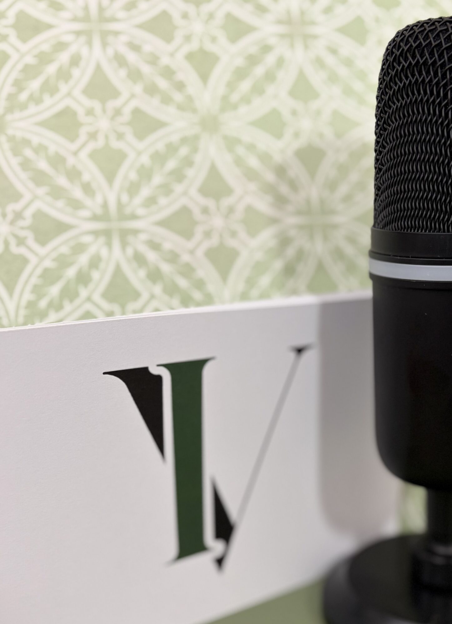 Close-up of a microphone on a table with a patterned green and white background.
