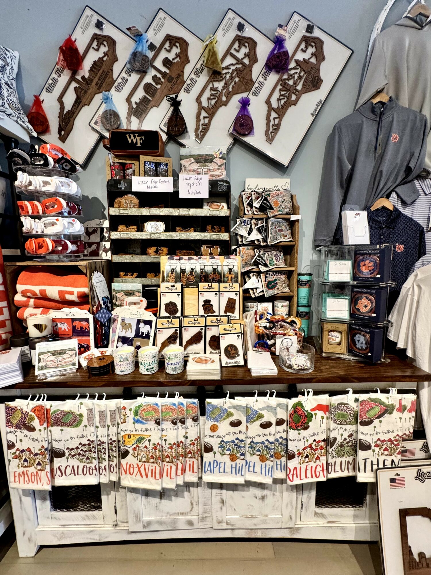Display of jewelry, accessories, and clothing in a retail store with artwork and signs in the background.