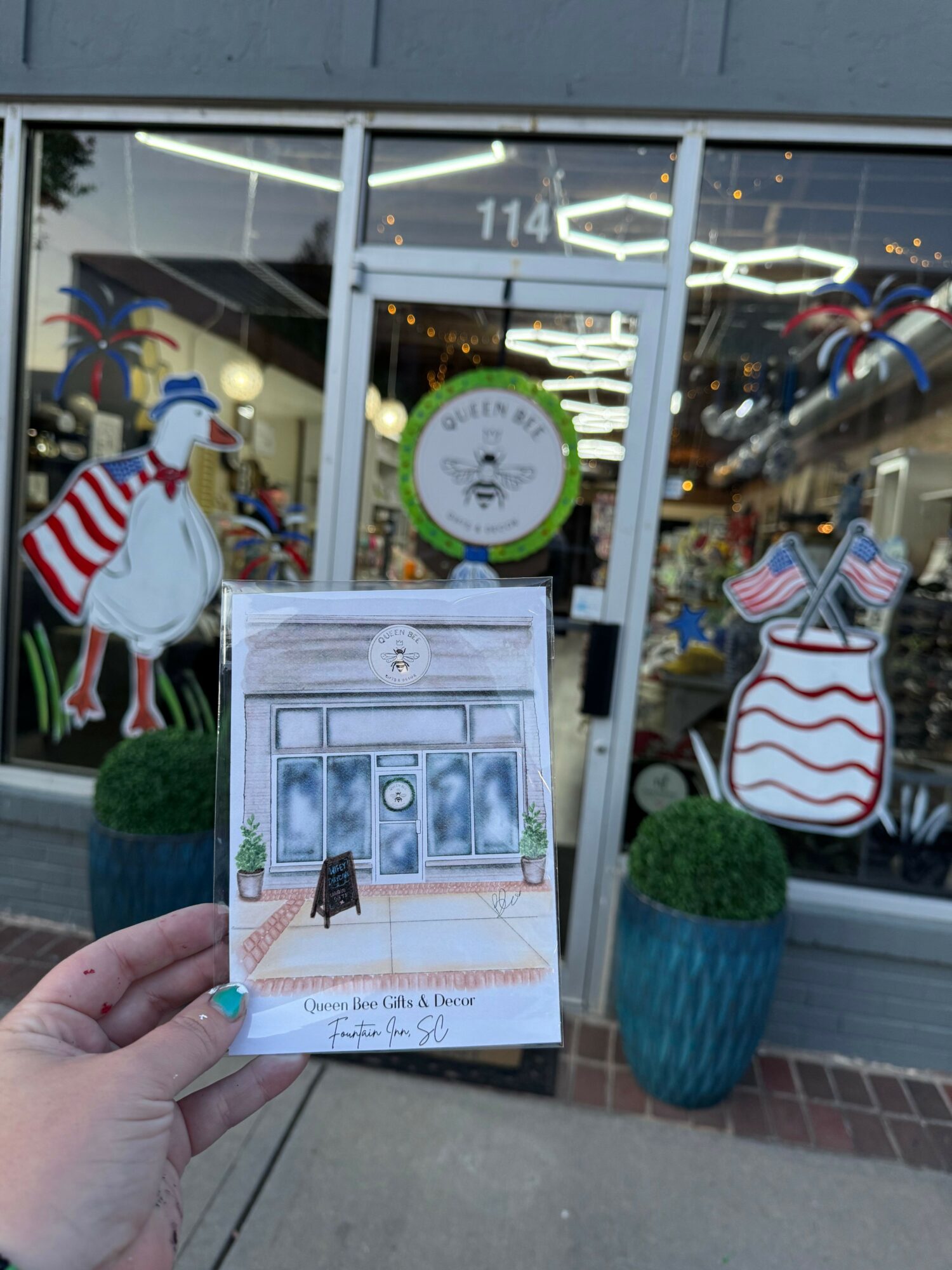 Person holding a flyer in front of a store window with holiday decorations and a reindeer figure outside.