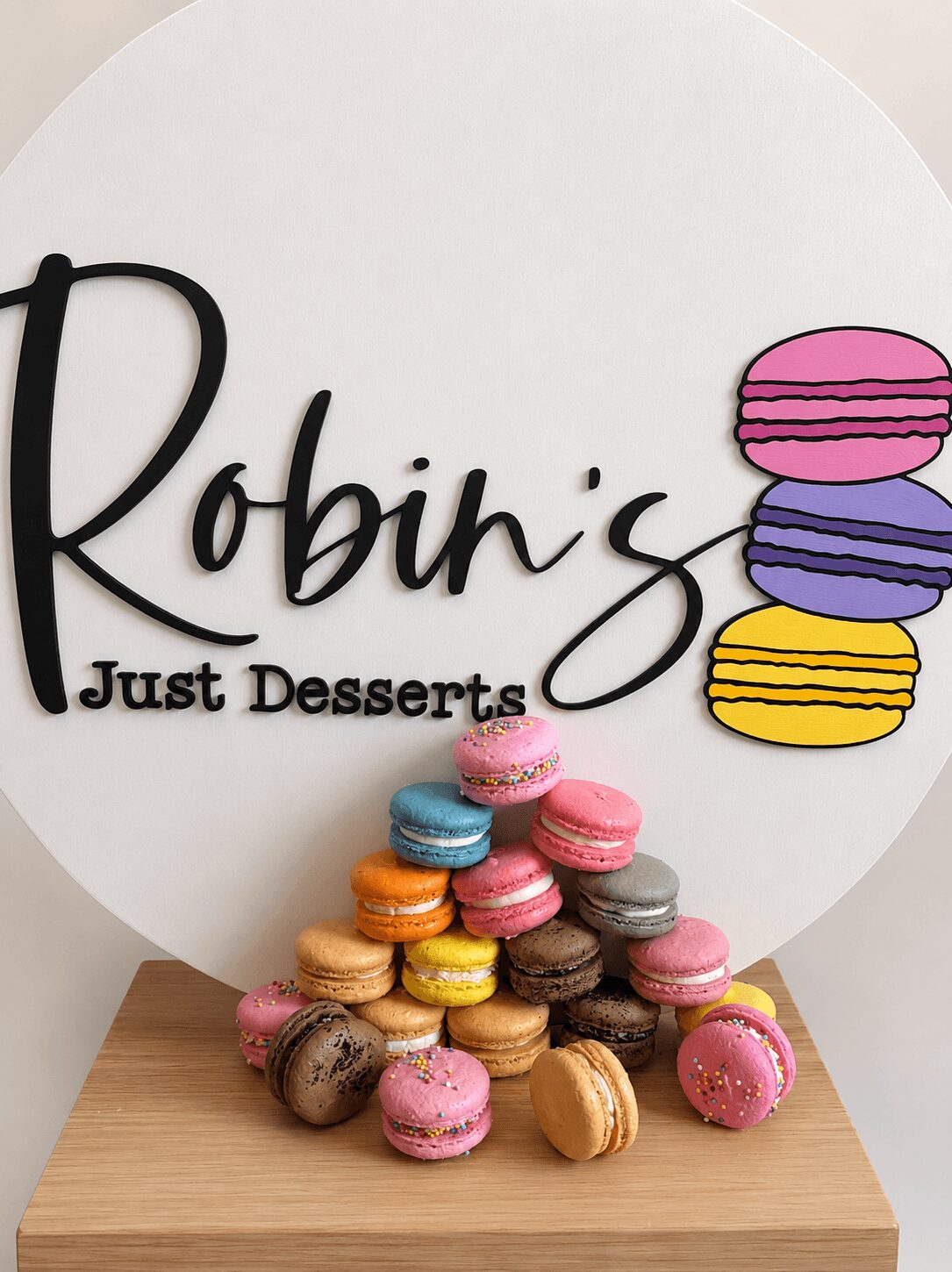 Colorful macarons stacked in front of a sign that reads