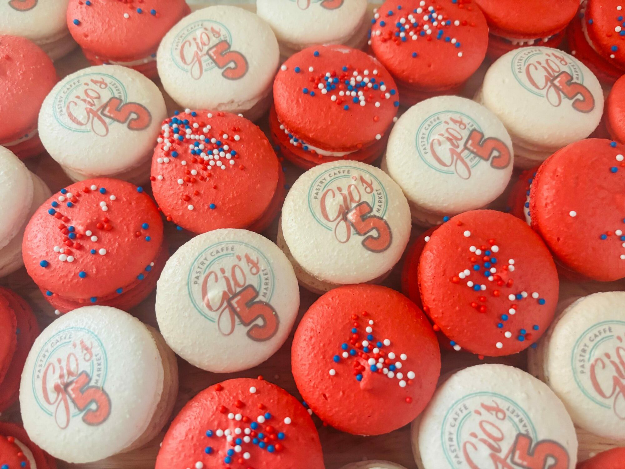 Colorful candies with red and white wrappers, some with sprinkles and text celebrating a fifth birthday, arranged closely together.