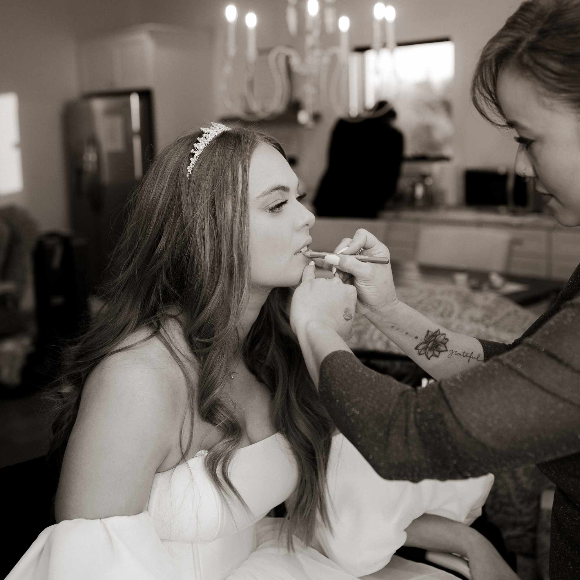Young woman getting makeup applied by a makeup artist in a room with kitchen background.