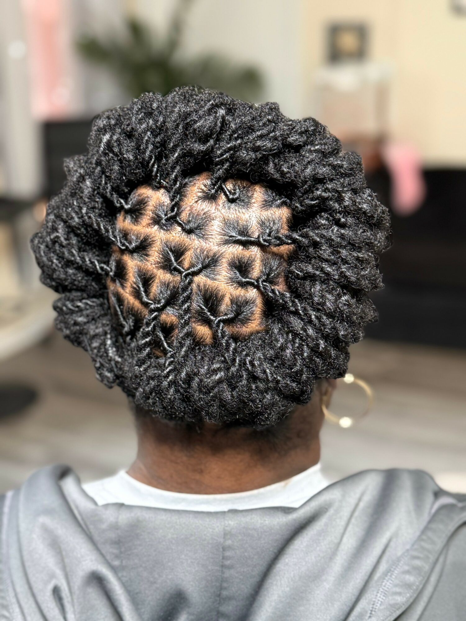 Back of a person's head with styled, textured black hair in twists, showing a pattern of small sections.
