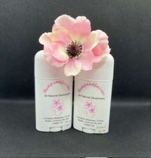 Two white deodorant sticks with pink floral labels, topped with a pink flower, against a dark background.