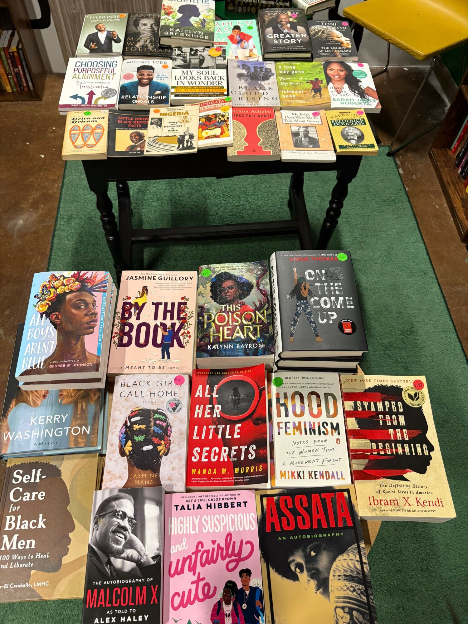 Books displayed on a black stand with a green carpeted floor background.