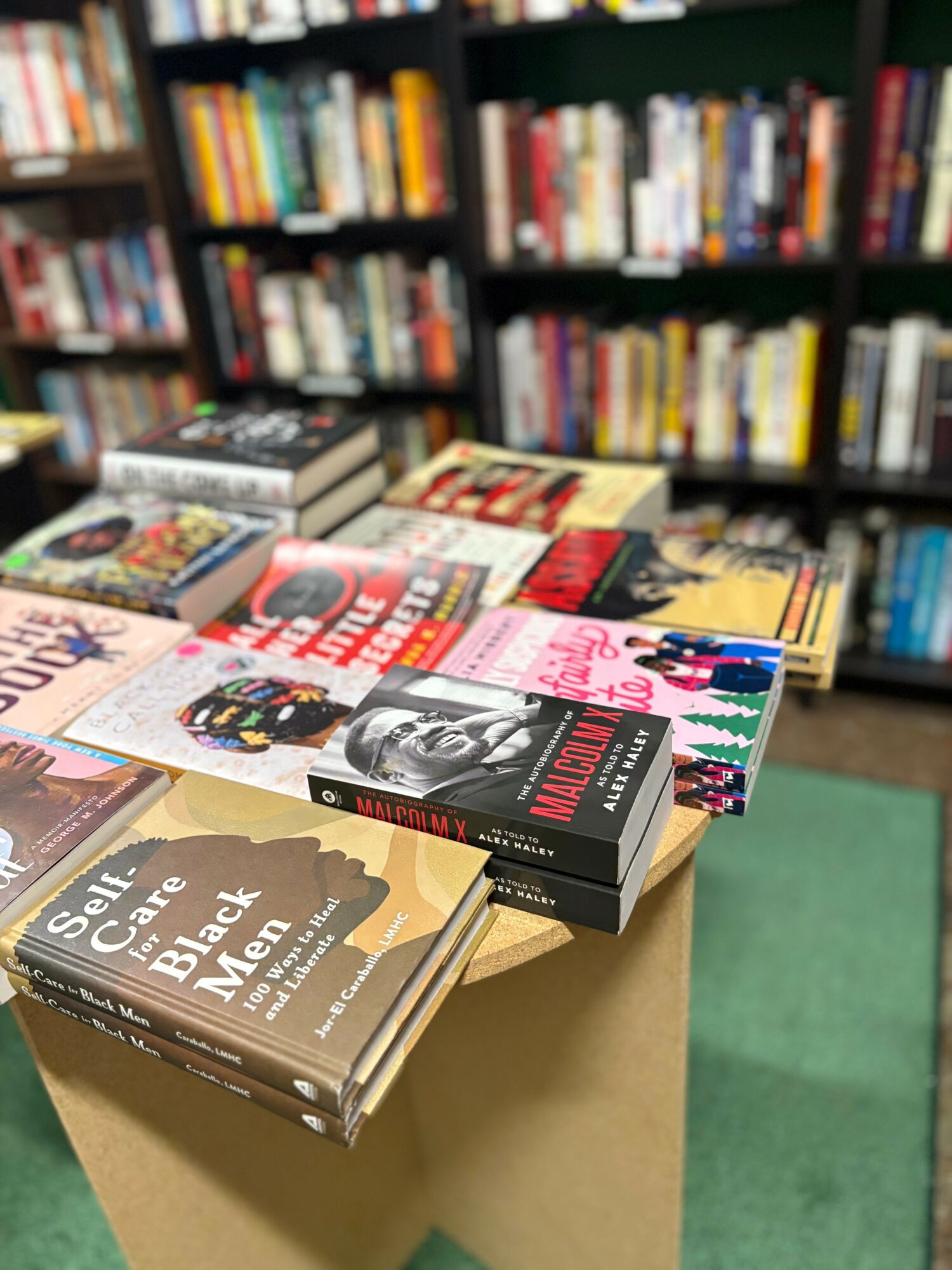 Books displayed on a table in a bookstore with shelves of books in the background.