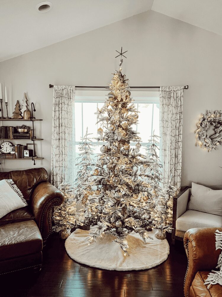 Decorated Christmas tree with snow-like ornaments in a living room, flanked by curtains and furniture, on a round rug.