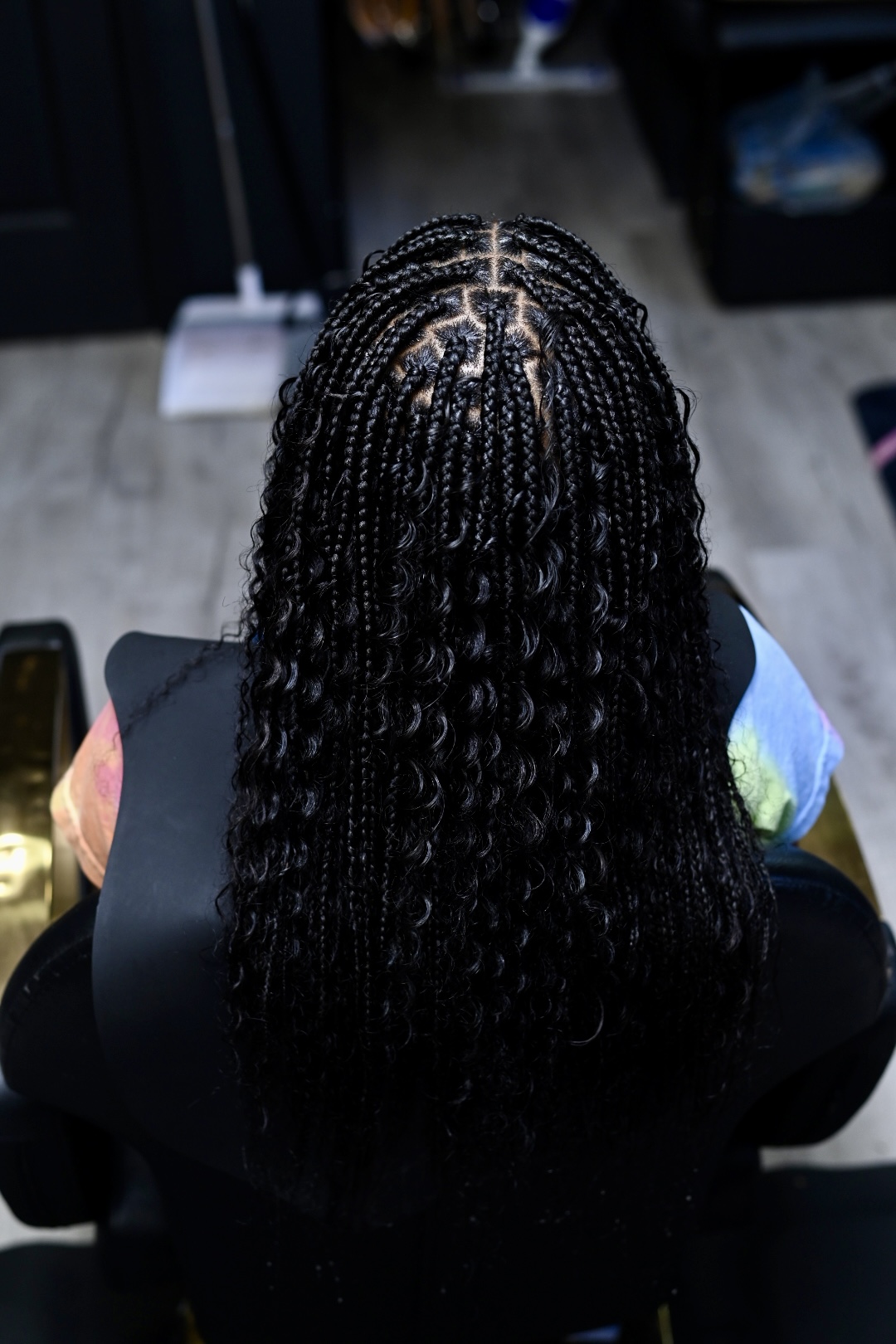Top view of a person with long, twisted braids, sitting indoors with a blurred background.