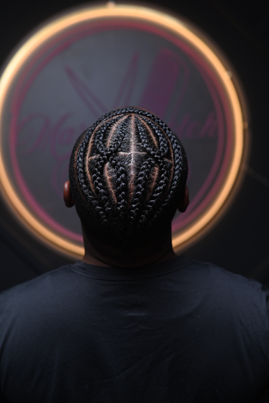 Person wearing a patterned mask with a circular neon sign in the background.