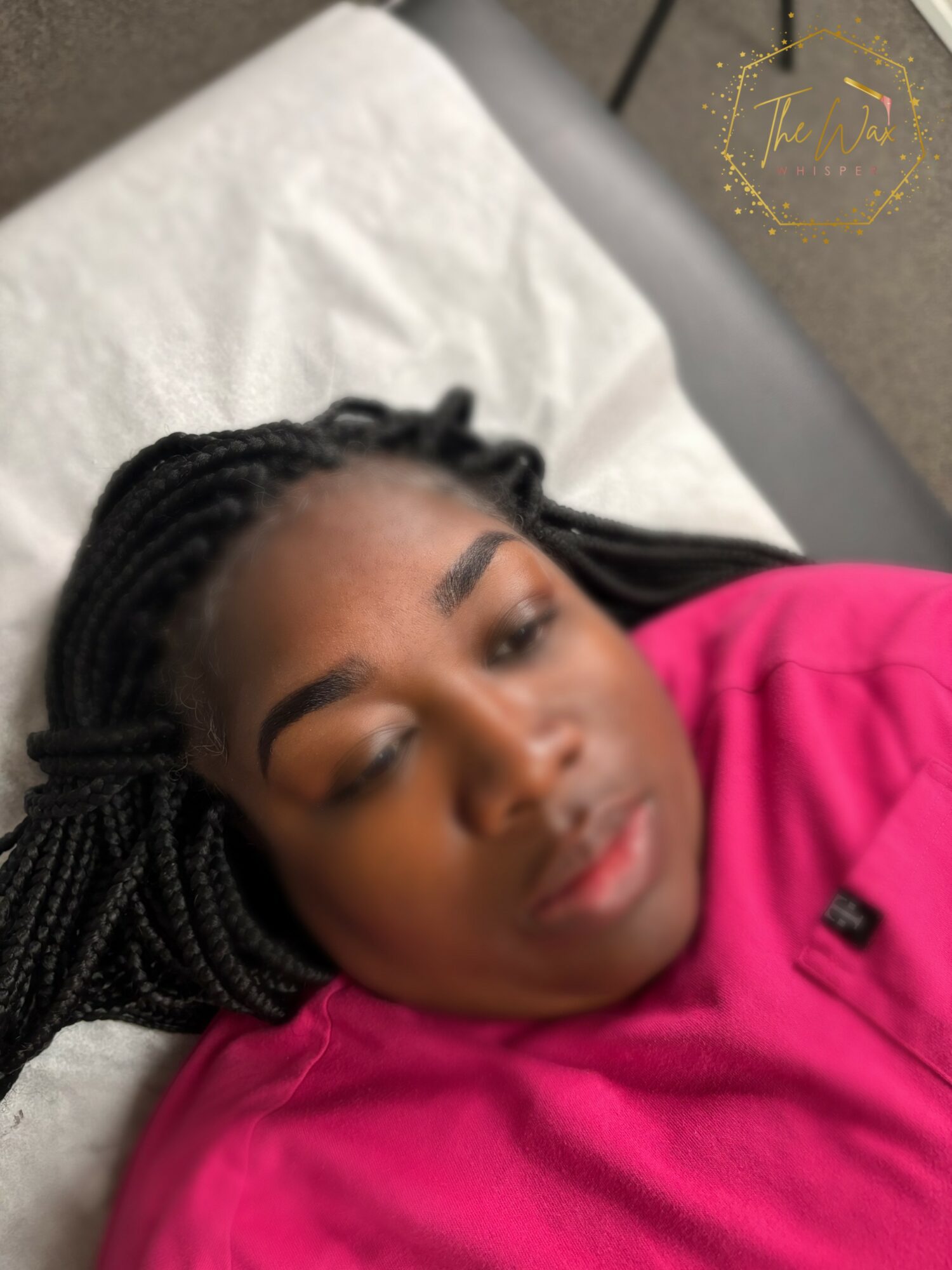 Young woman with braided hair lying on a pillow, wearing a pink top, eyes closed, relaxed.