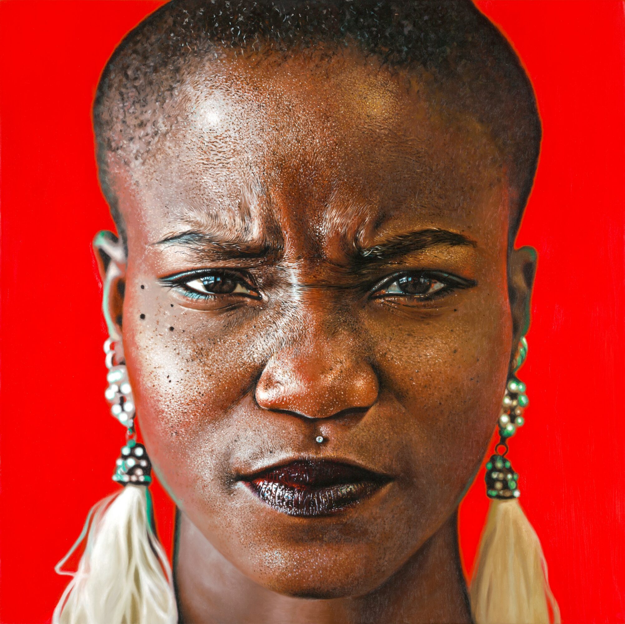 Close-up of a woman with short hair, dark lipstick, earrings, and a serious expression against a red background.