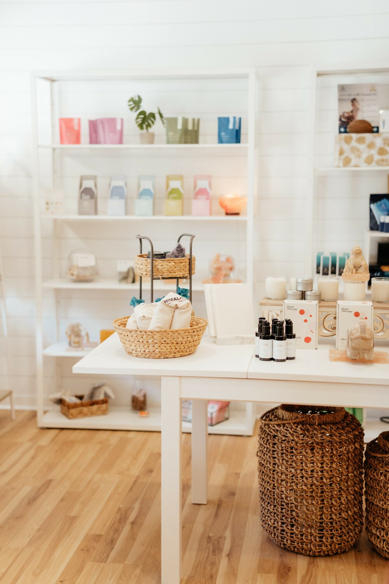 Display shelves with colorful products and a table with baskets and bottles in a bright store interior.