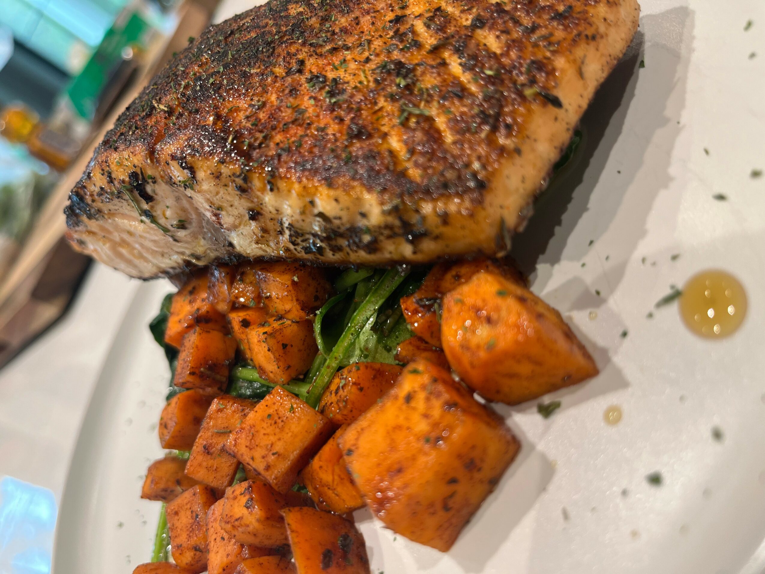 Cooked fish fillet with seasoned roasted potatoes and green vegetables on a plate.