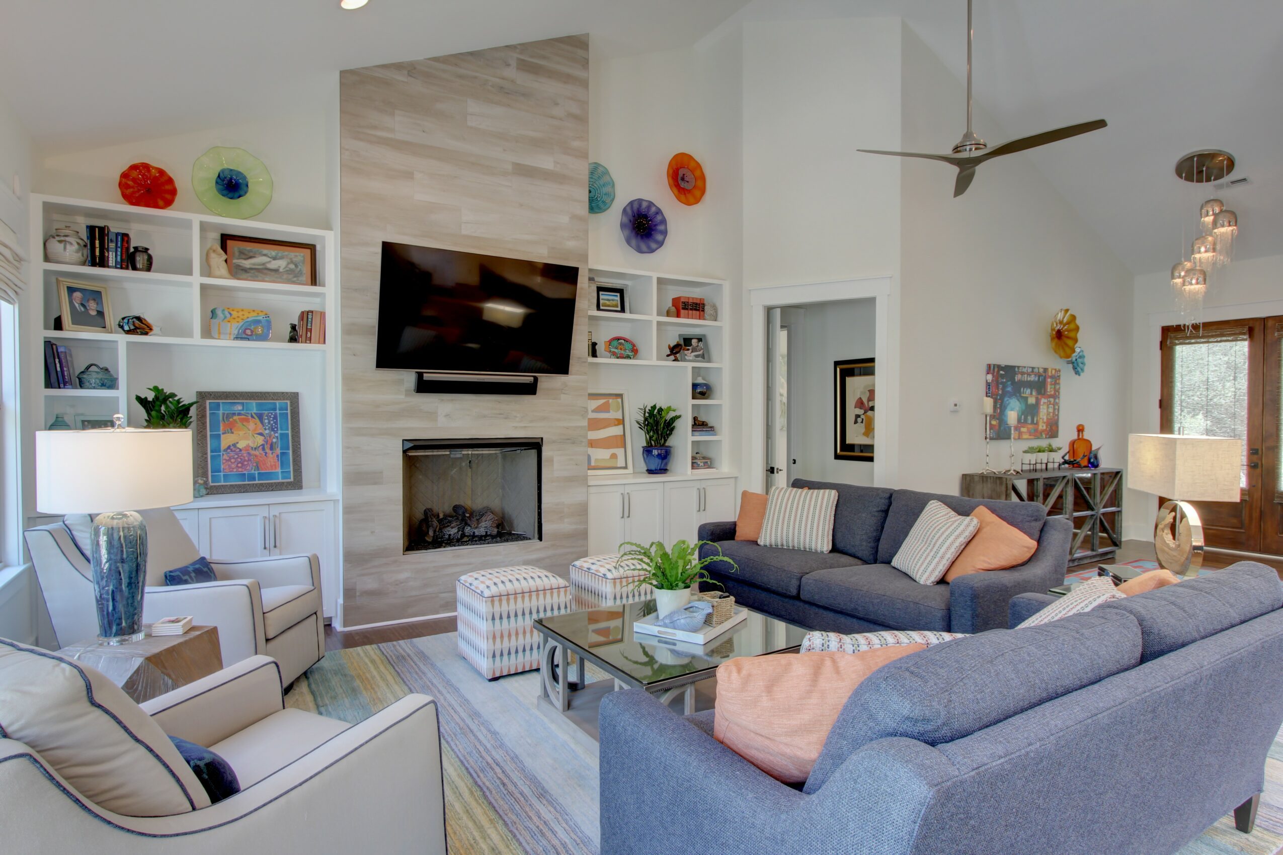 Living room with a fireplace, wall-mounted TV, blue sofa, armchair, and built-in shelves with decorations.