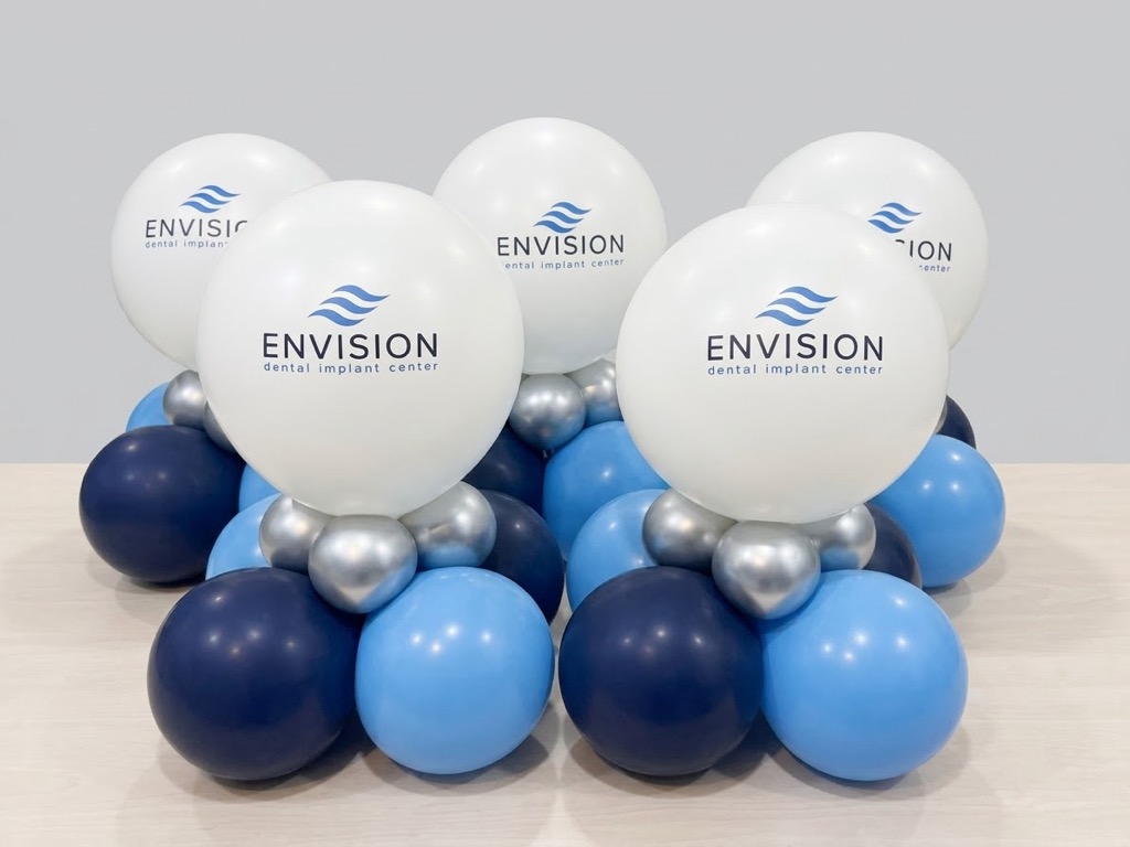 Cluster of balloons with white, blue, and silver colors, featuring the Envision logo, on a light background.