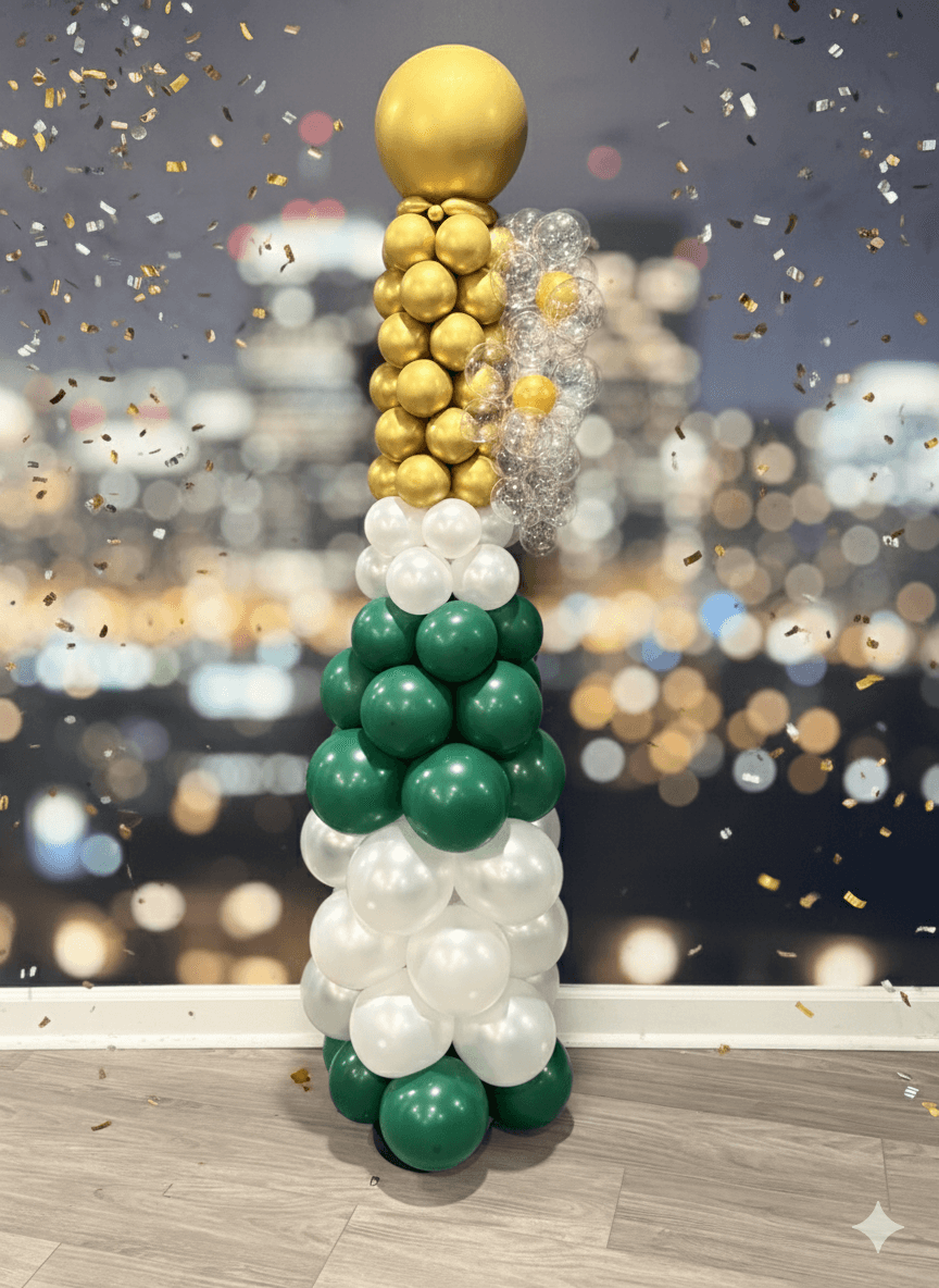 Tall balloon sculpture with gold, white, and green balloons, topped with a large gold balloon, against a blurred cityscape background.